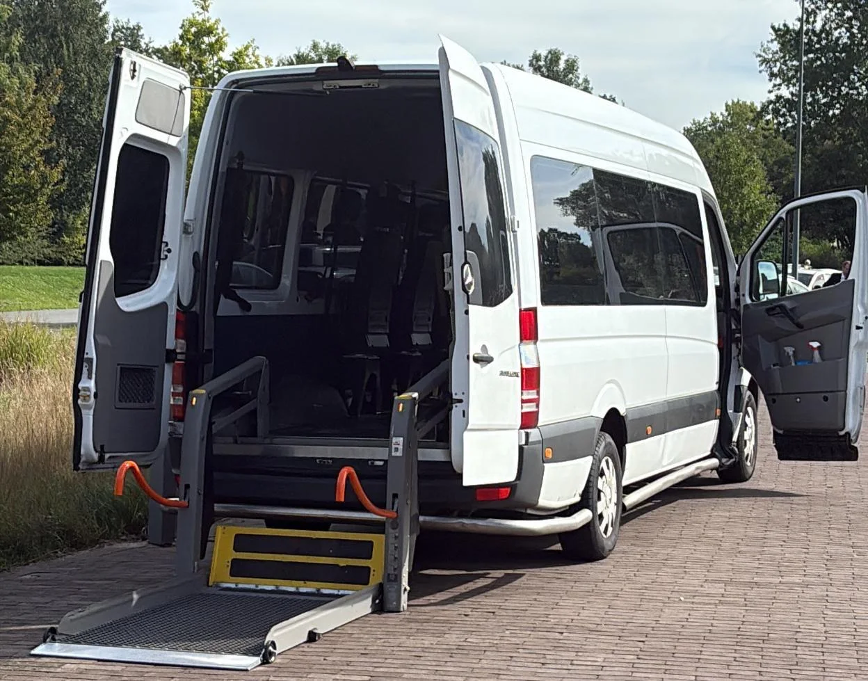 Witte rolstoeltaxi met geopende deuren en rolstoellift